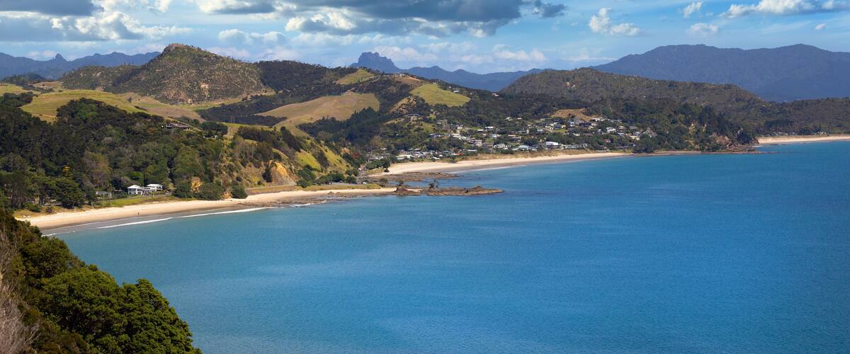 A coastal landscape with a beach, hills, and a clear sky.