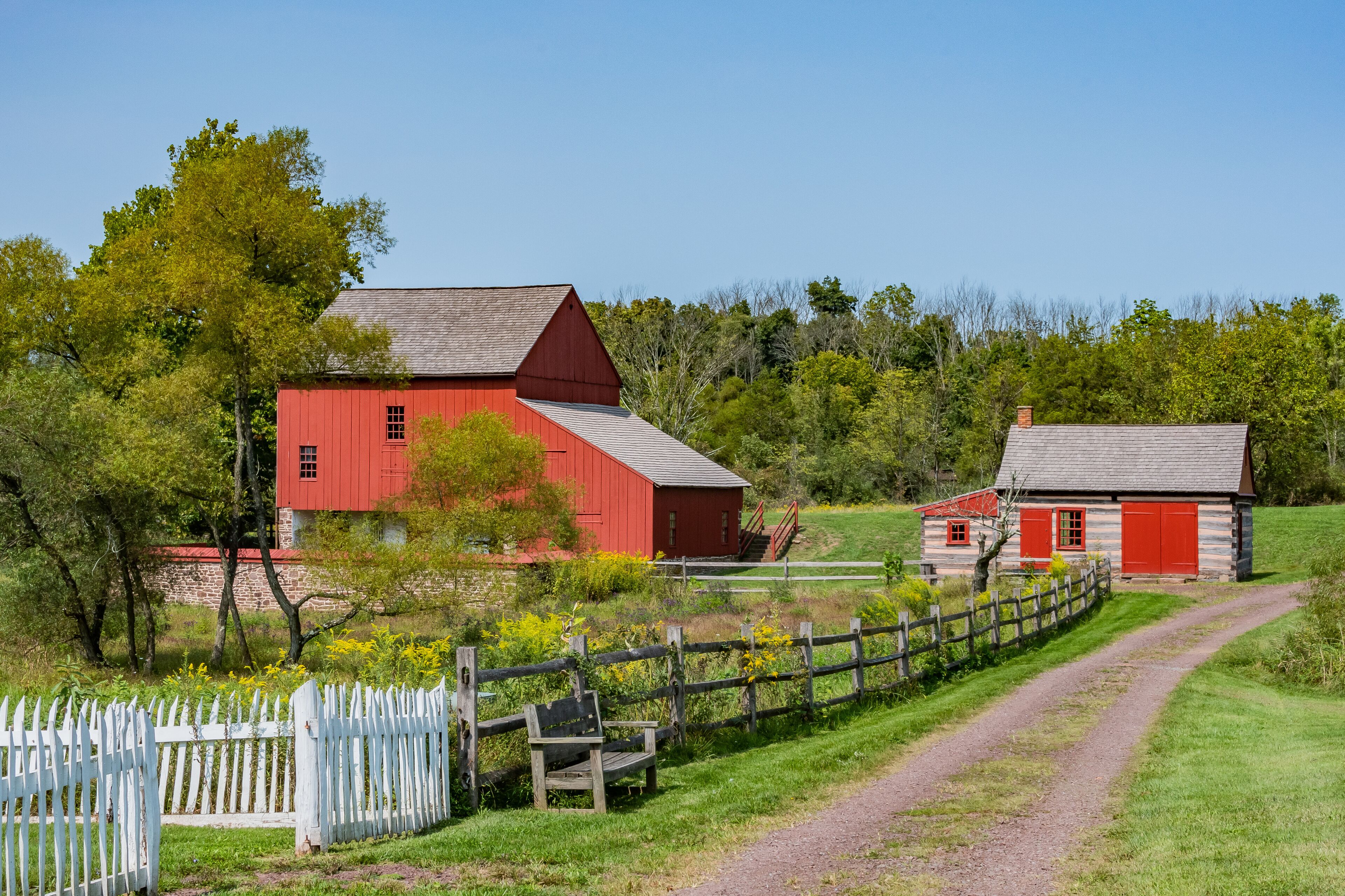 A red barn, a white picket fence, and a dirt path.