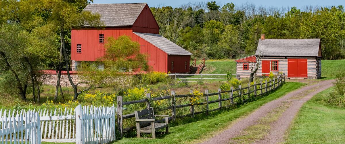 A red barn, a white picket fence, and a dirt path.