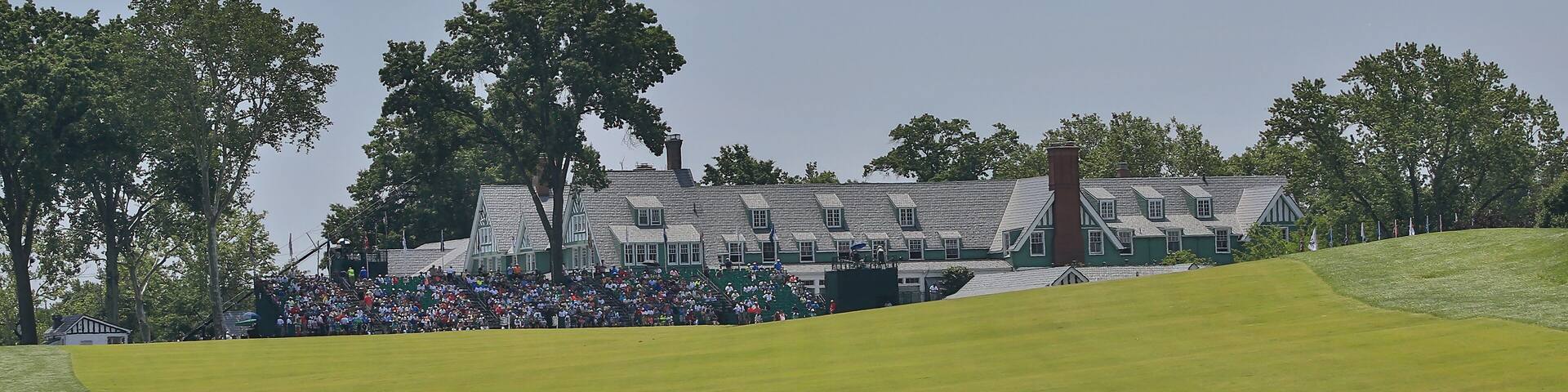 Un campo de golf con un club de campo y espectadores.
