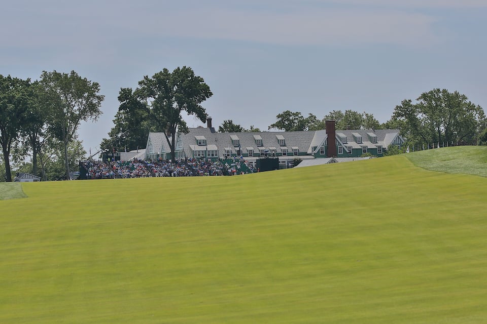 Campo de golfe com clube e espectadores.