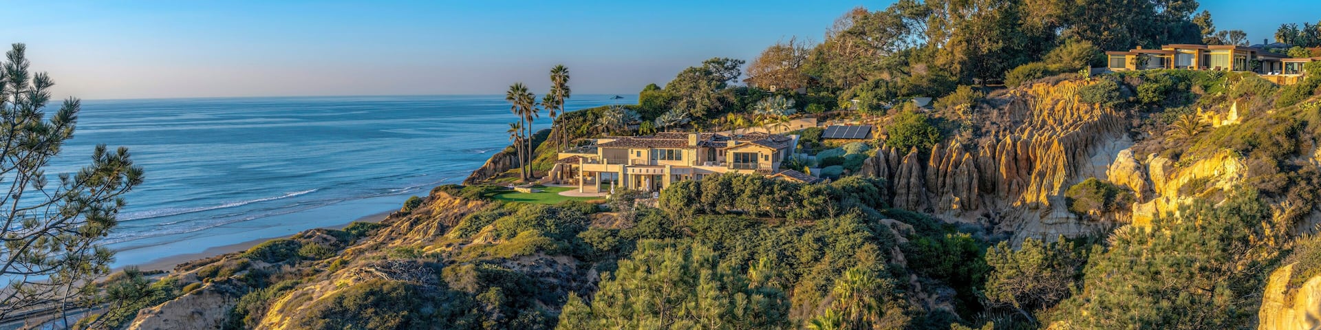 A coastal landscape with houses on a cliff overlooking the ocean.