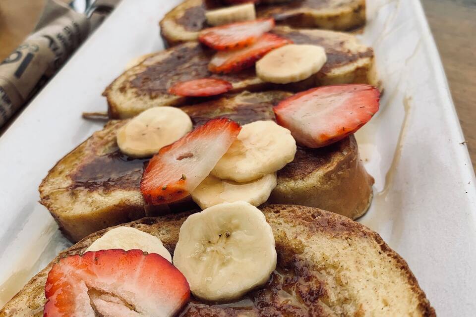 French toast topped with strawberries and bananas on a white plate.