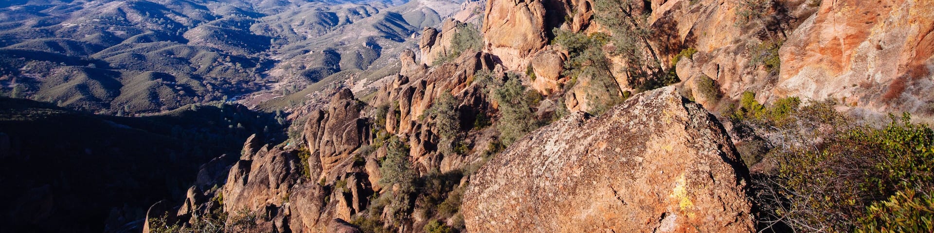 A rugged mountain landscape with rocky cliffs and sparse vegetation.