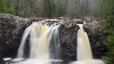 Una cascada que se precipita sobre rocas en un área boscosa.