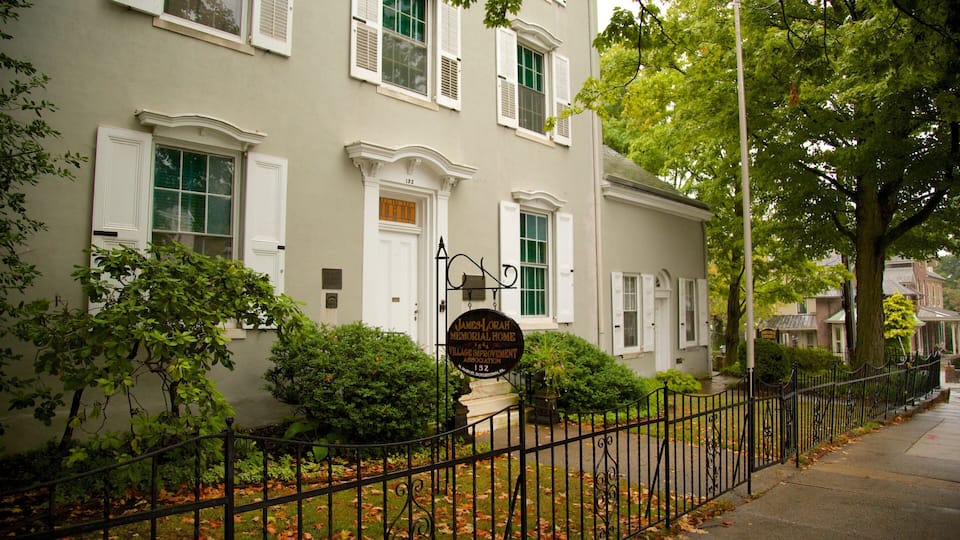 A historic building with white shutters and a plaque reading "James Lorah Memorial Home Village Improvement Association."