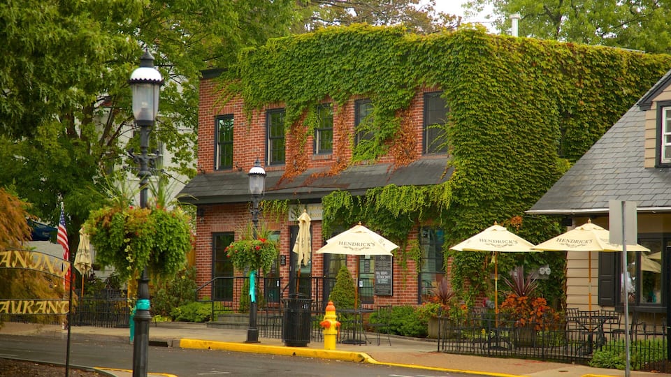 A brick building with ivy covering the upper part, outdoor seating with umbrellas, and a yellow fire hydrant on the sidewalk.