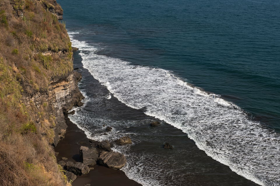 A coastal cliff with waves crashing against the rocks.