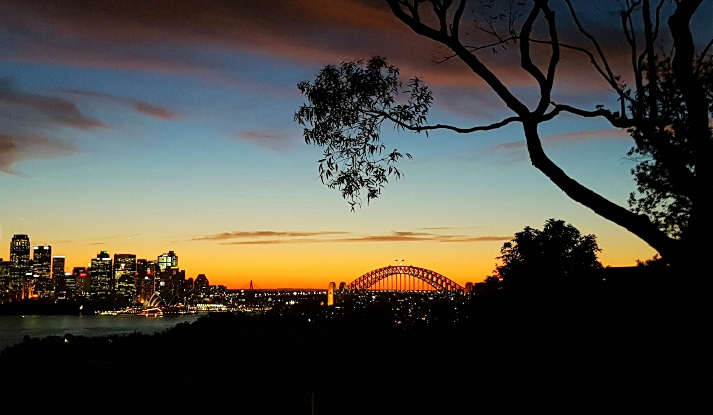 Silueta del Puente de Sydney contra un cielo colorido al anochecer.