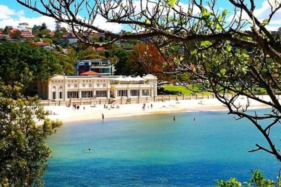 Vistes costaneres amb una platja, un edifici gran i un cel blau clar.