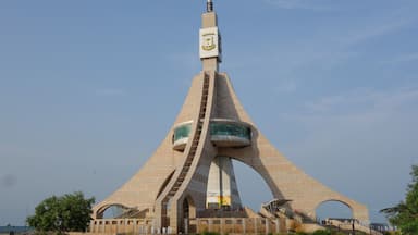 A modern architectural structure with a tall spire and multiple arched openings.
