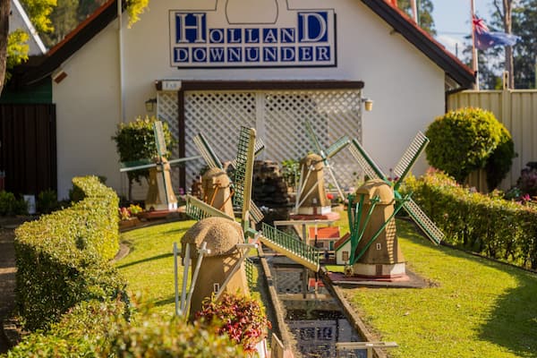 En vindmølle, en bygning med skiltet 'HOLLAND DOWNUNDER', og velholdt beplantning.