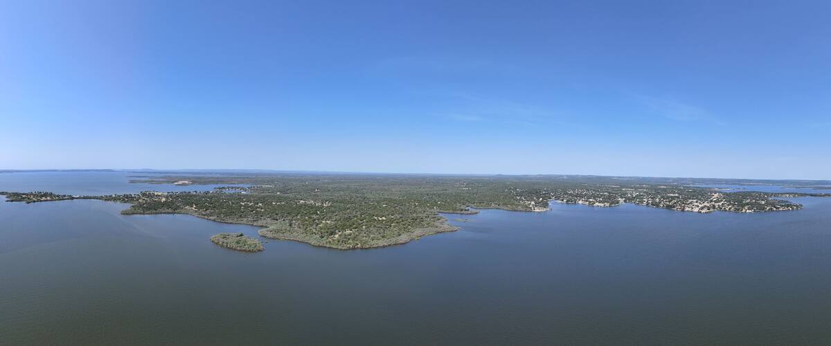 An aerial view of a coastal region with a large body of water, several small islands, and a dense green landscape.