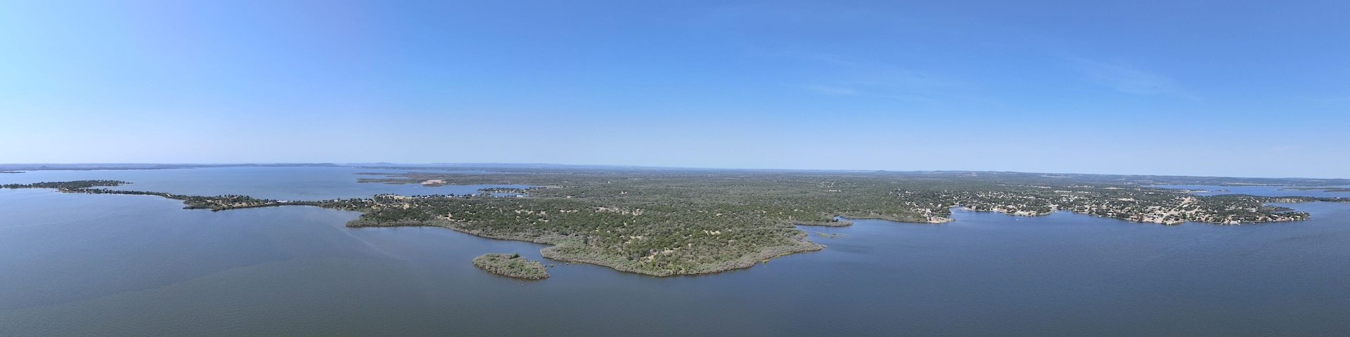 An aerial view of a coastal region with a large body of water, several small islands, and a dense green landscape.