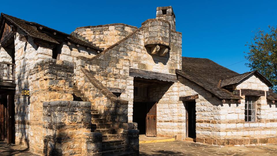 A historic stone building with a steeply pitched roof, a wooden door, and a small window.