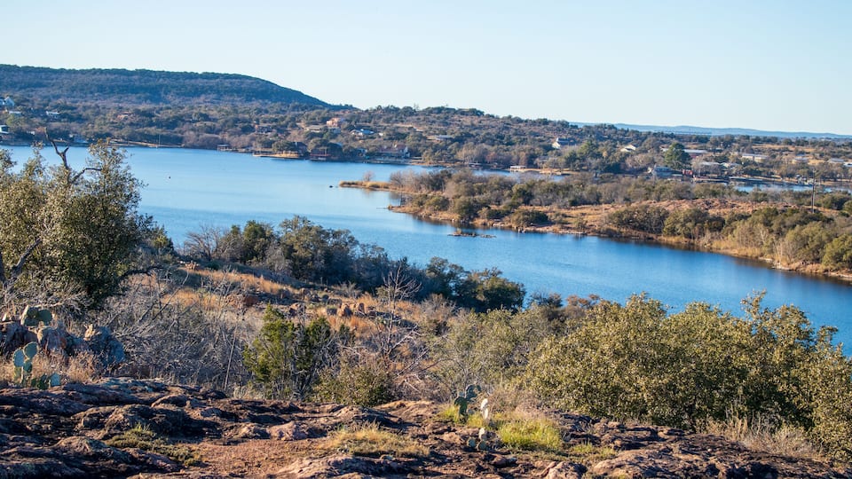A river winding through a hilly landscape with sparse vegetation and a few scattered buildings.