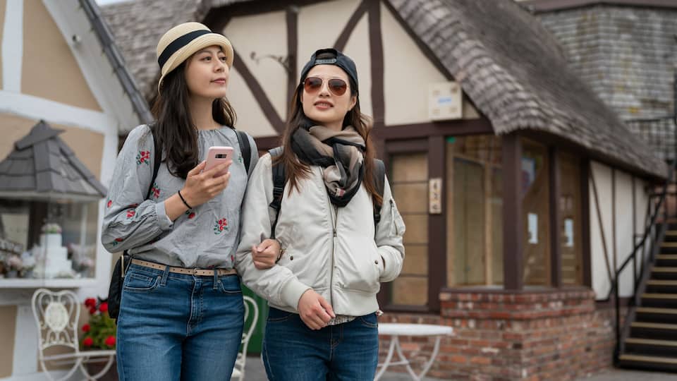 Two people standing in front of a building with a thatched roof and exposed timber framing.