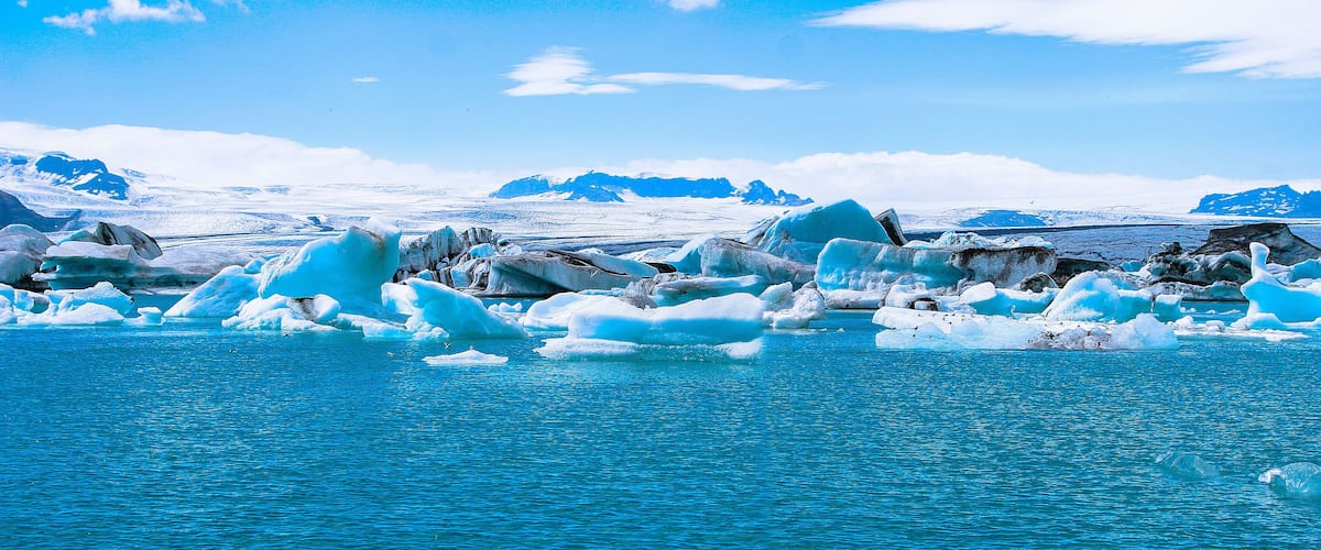 A glacier with floating icebergs in a turquoise body of water.