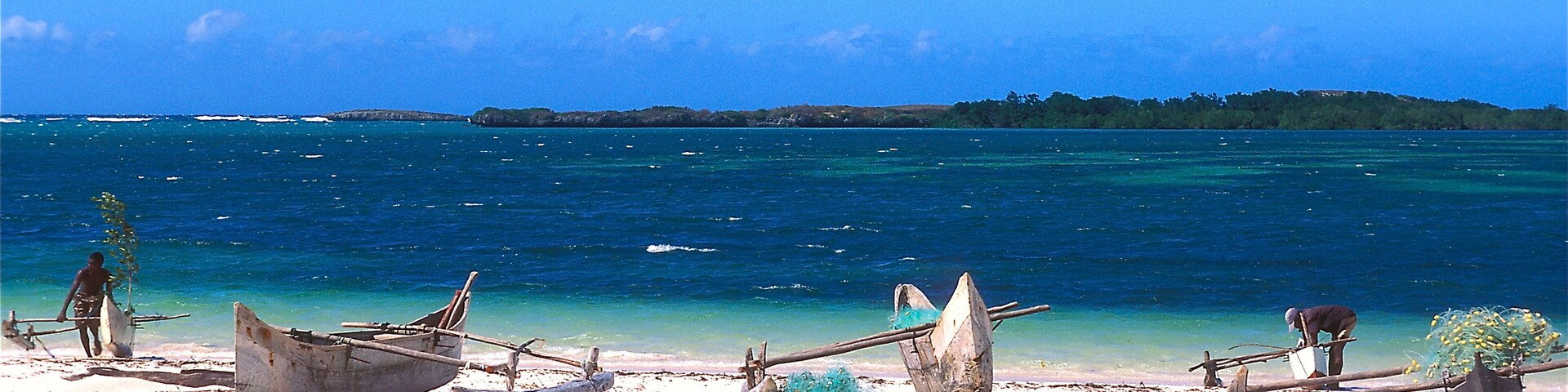 Una playa con barcos y un mar azul y cristalino.