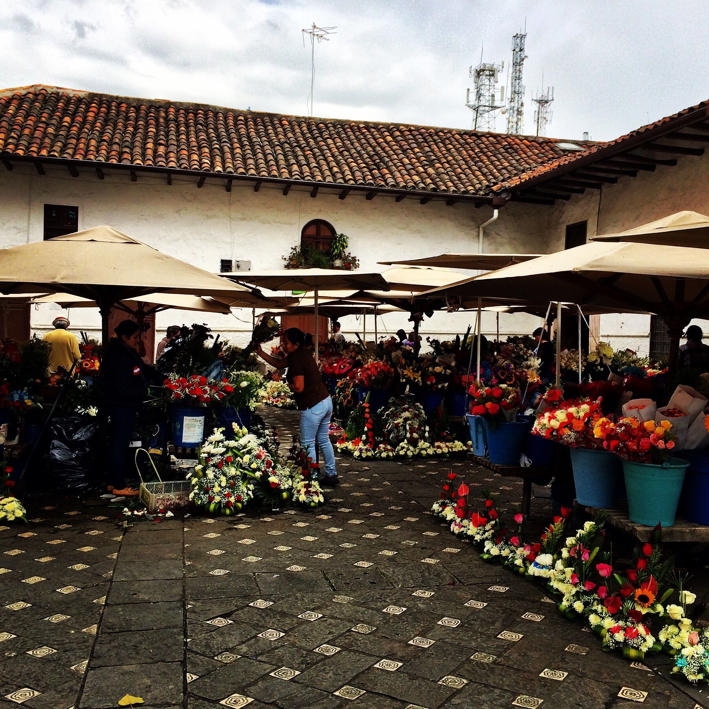 An outdoor flower market with vendors and customers.