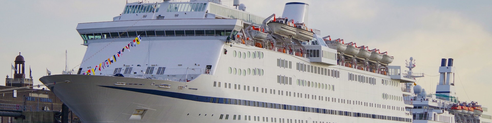 Classic British cruiseship cruise ship liner docked in Tilbury, London UK on River Thames seen from excursion boat with flying flag Union Jack