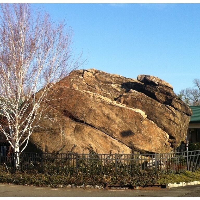 A large rock formation with a fence in the foreground.