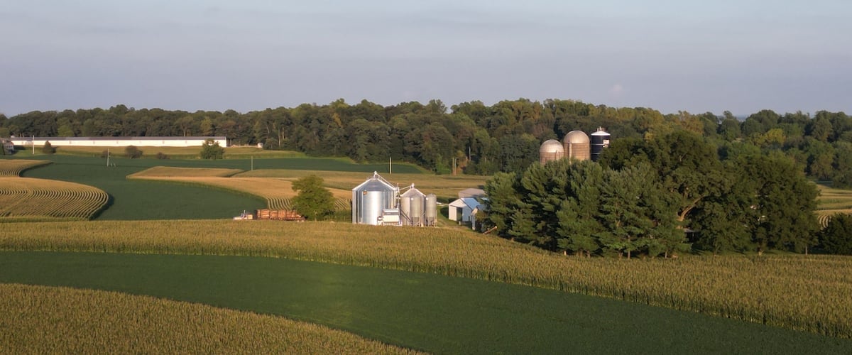 A rural landscape with fields, barns, and silos.