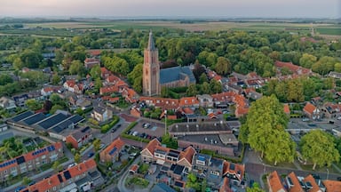 An aerial view of a town with a prominent church tower, surrounded by residential buildings and lush greenery.