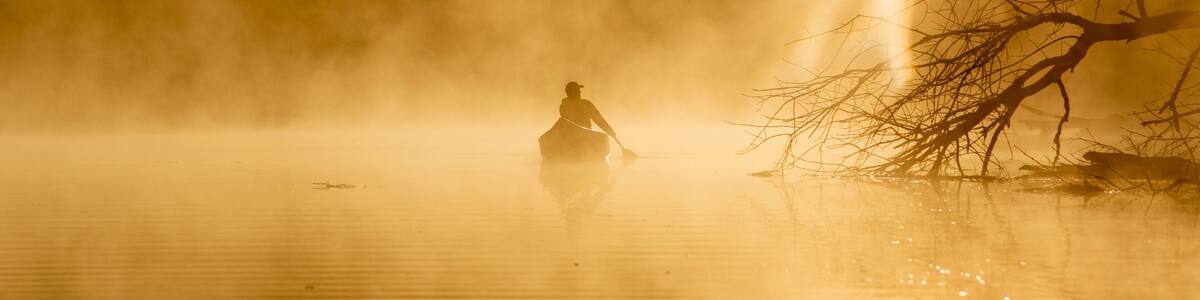 Sunrise canoe ride on foggy river.