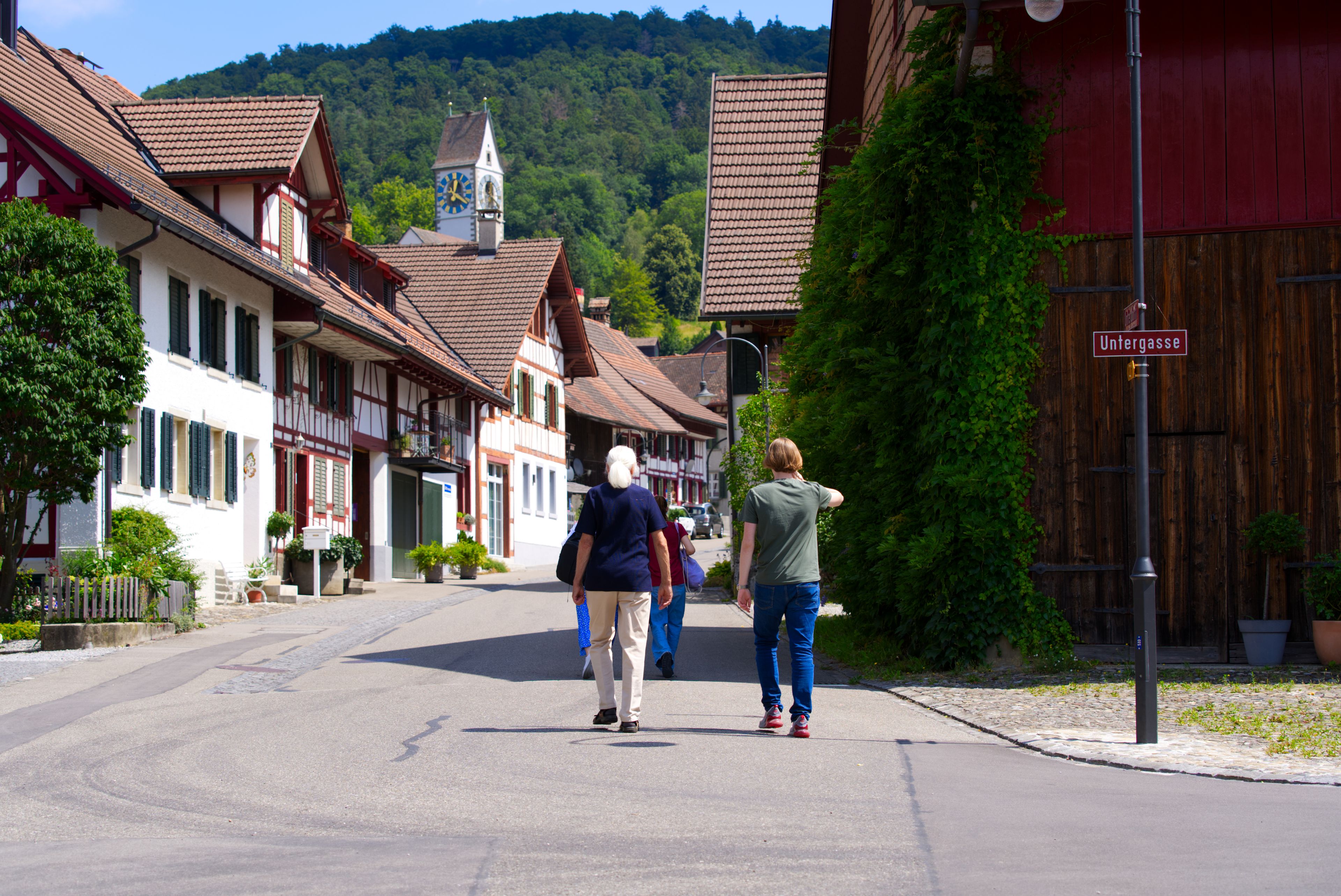 A street in a European town with traditional half-timbered houses, a church steeple, and a sign reading 'Untereggasse.'