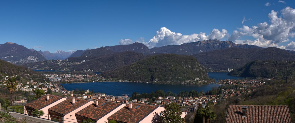 A mountainous landscape with a lake, a town, and a villa.