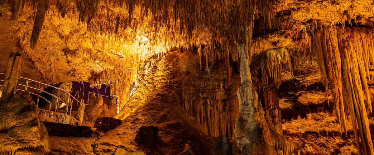 A cave with stalactites and a metal walkway.