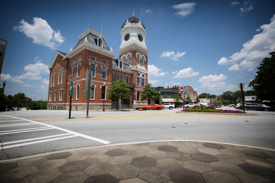 An older American County Courthouse with an older 1969 muscle car parked in front. ..