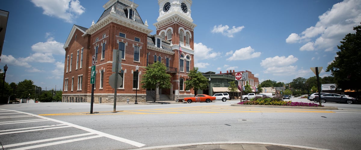 An older American County Courthouse with an older 1969 muscle car parked in front. ..