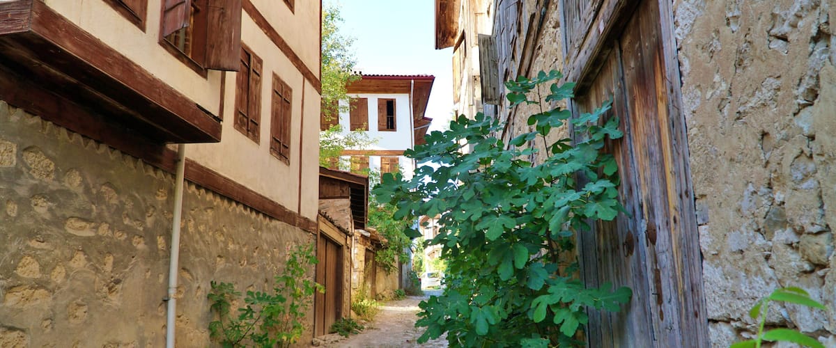 Una stretta strada acciottolata, fiancheggiata da edifici tradizionali con persiane in legno e pareti in pietra.