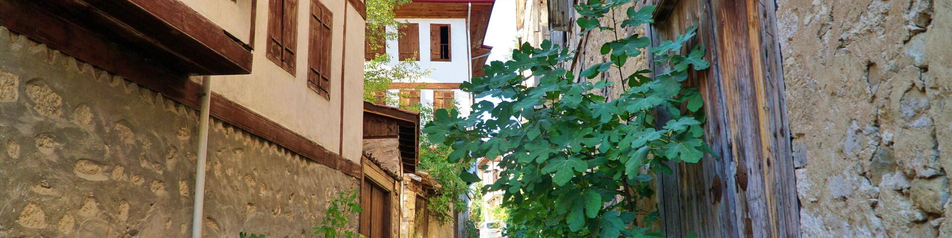 Una estrecha calle empedrada flanqueada por edificios tradicionales con contraventanas de madera y paredes de piedra.