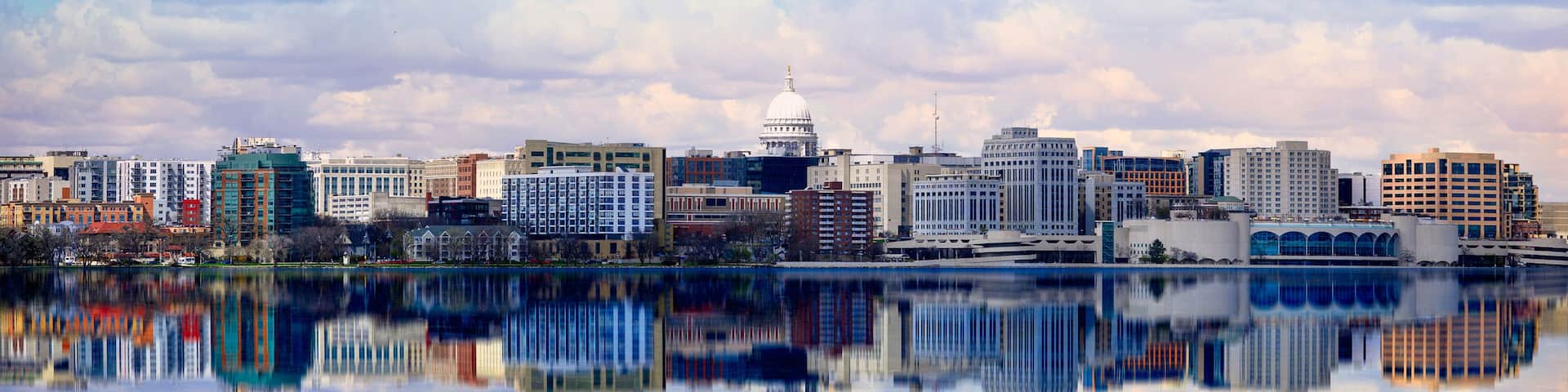 A city skyline with a prominent white dome building, reflecting in a calm body of water.