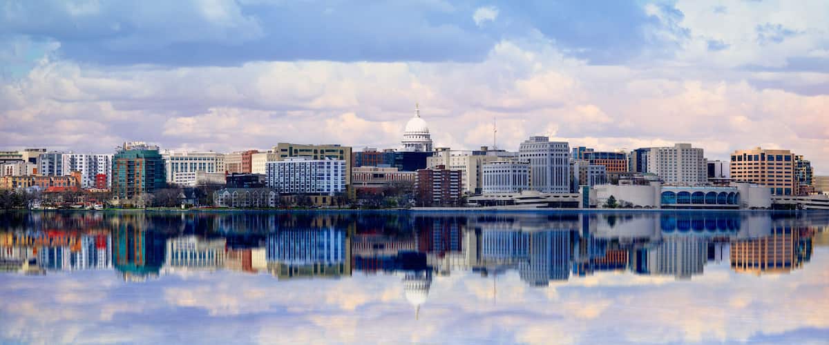 A city skyline with a prominent white dome building, reflecting in a calm body of water.