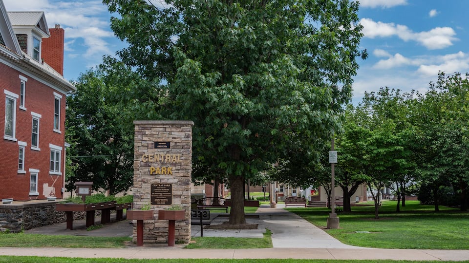 A stone monument labeled "Central Park" surrounded by benches and trees.