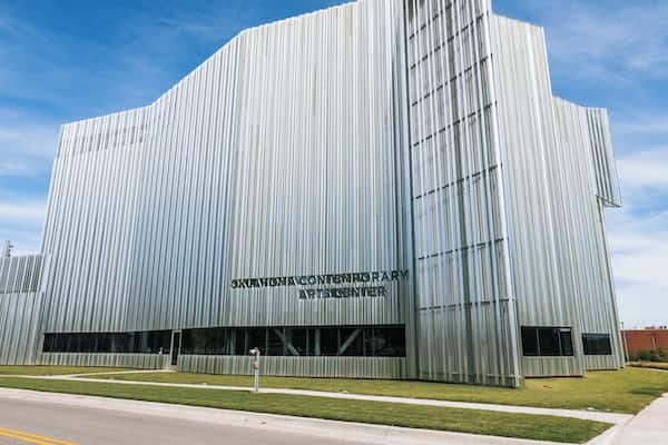 A modern building with vertical lines, labeled as 'OKLAHOMA CONTEMPORARY ARTS CENTER'.