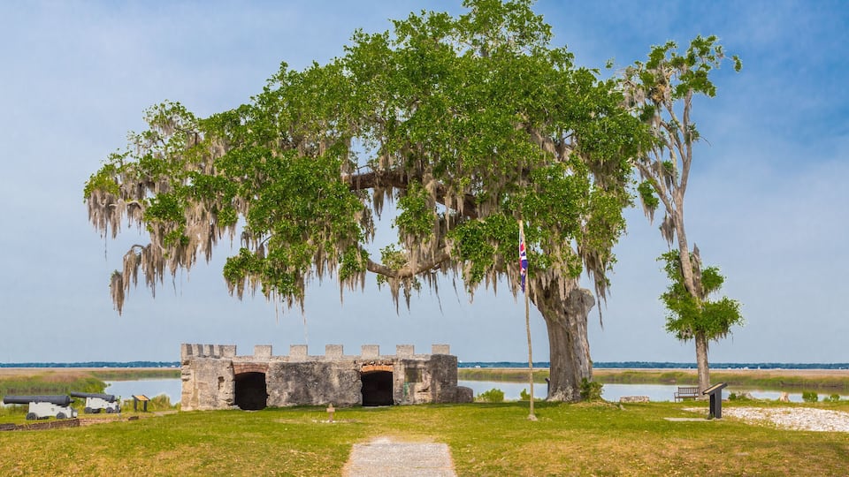 A historic fort with a large tree in the foreground and a clear sky.