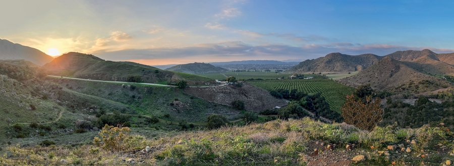 Panorama of hills, mountains, green valleys with citrus orchards and farming fields as the sunsets in southern California countryside