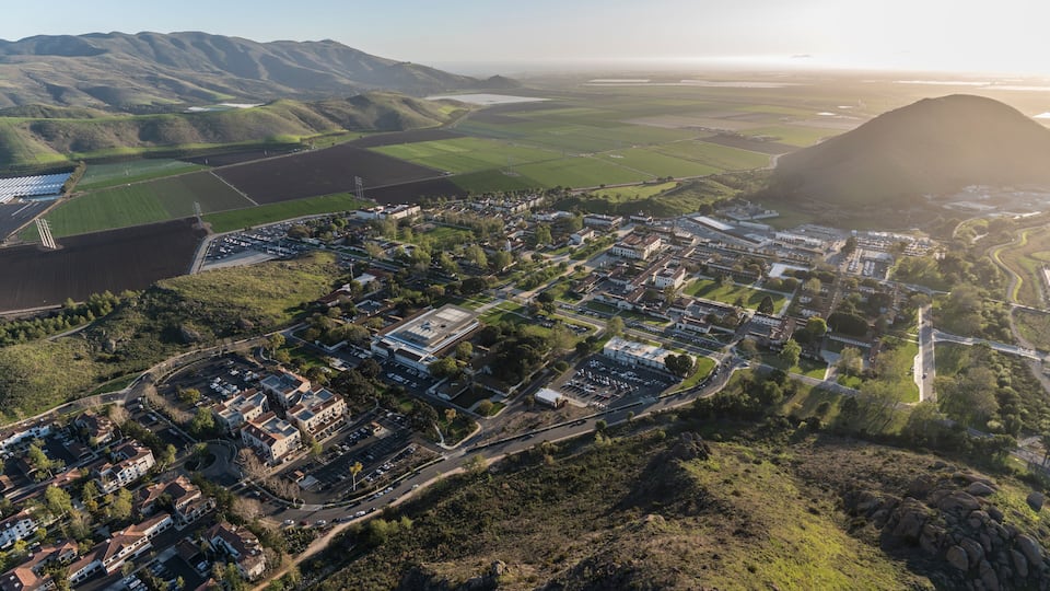 An aerial view of a town with residential areas, roads, and surrounding hills.