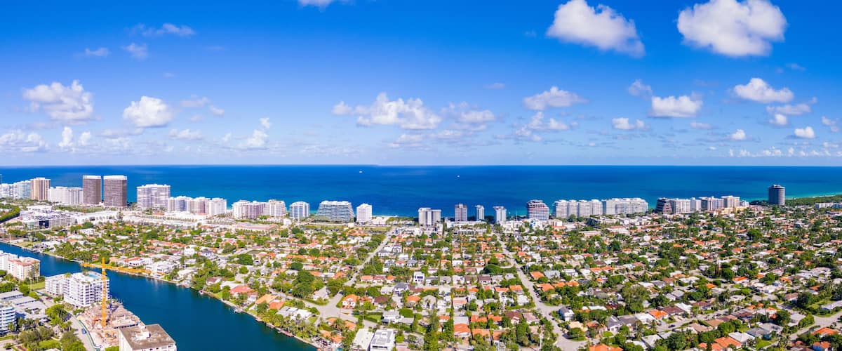 A coastal cityscape with dense residential areas, a marina, and a clear blue sky.