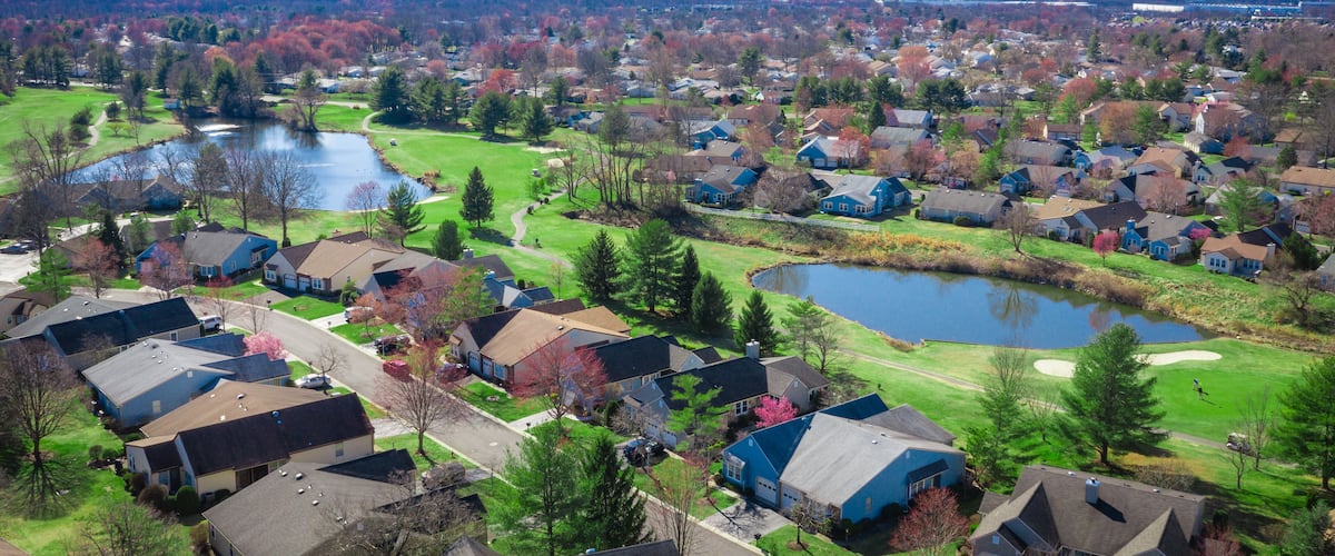 A residential area with houses, a golf course, and a lake.