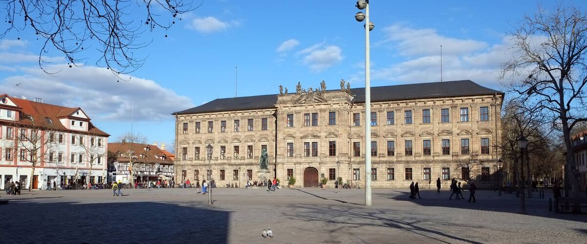 A historic building with classical architecture, a cobblestone square, and leafless trees.