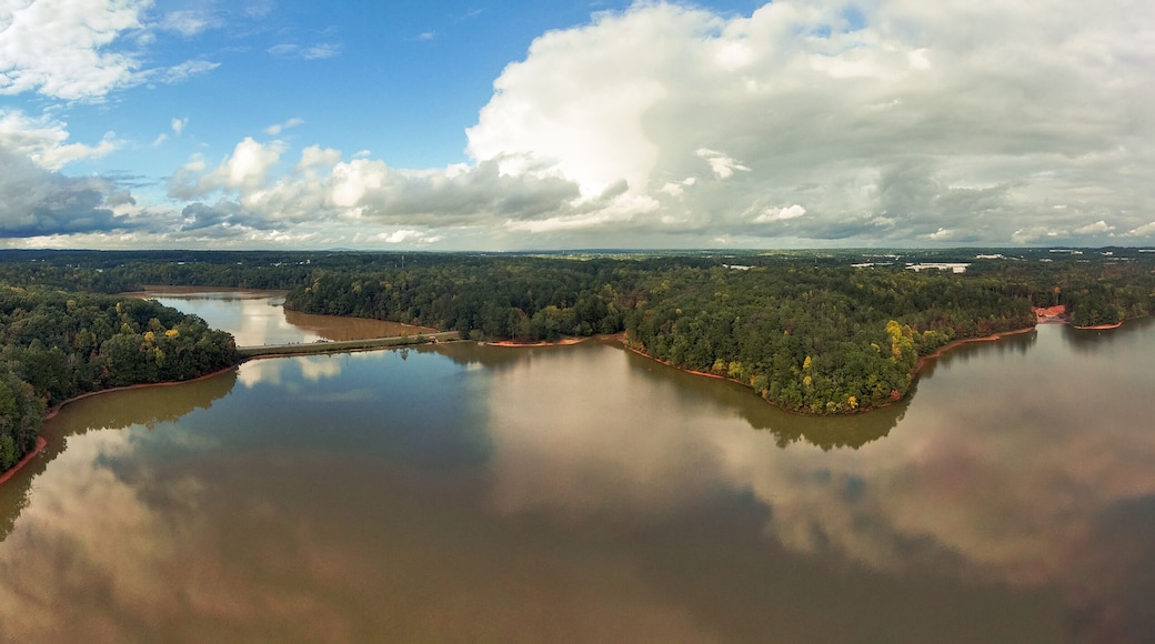 a breathtaking panoramic aerial shot of the still lake waters and vast miles of lush green and autumn colored trees with powerful cloud formations and blue sky at Sweetwater Creek State Park