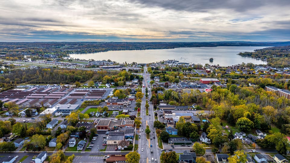 An aerial view of a town with a river, industrial buildings, and autumn foliage.