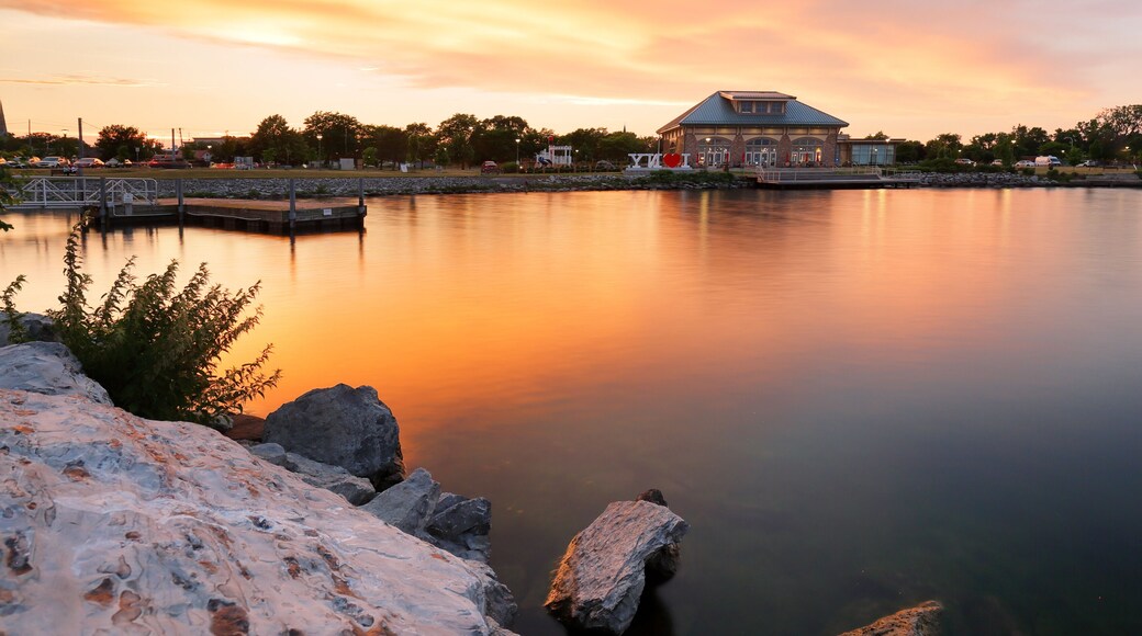 Een kalm meer bij zonsondergang, met een gebouw en een steiger op de achtergrond.
