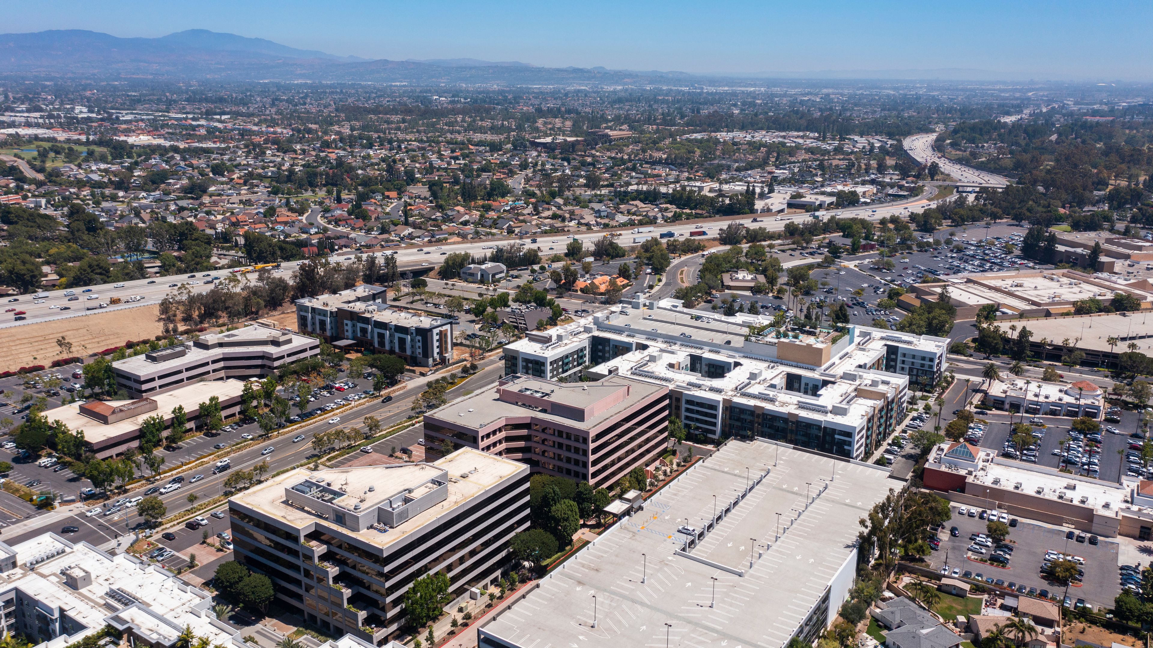 A cityscape with a prominent highway, commercial buildings, and a mountainous backdrop.